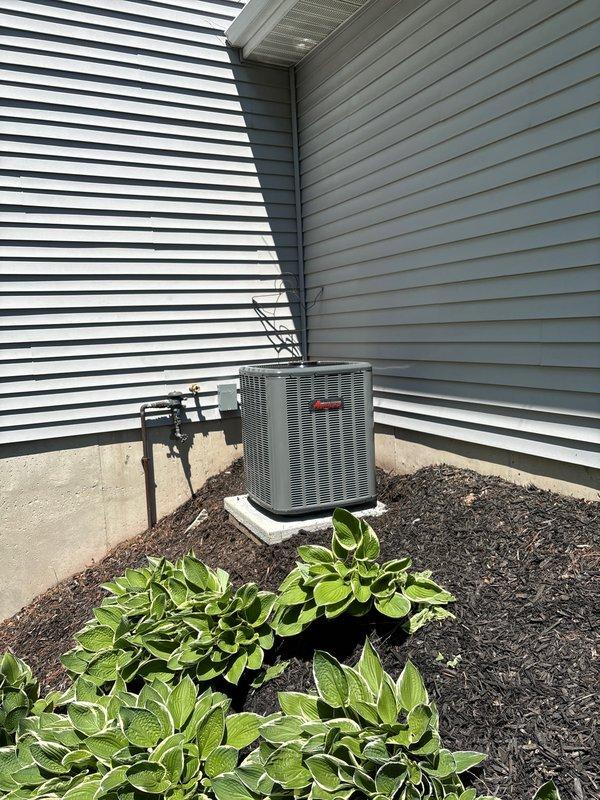 Completed full HVAC system installation including new furnace and air conditioning unit. Installed white furnace in basement utility area with proper ductwork connections, PVC condensate drainage lines, and electrical wiring per manufacturer specifications. Mounted outdoor condenser unit on concrete pad in exterior corner location between buildings, connected refrigerant lines to indoor unit, and verified proper system operation and refrigerant charge upon startup.