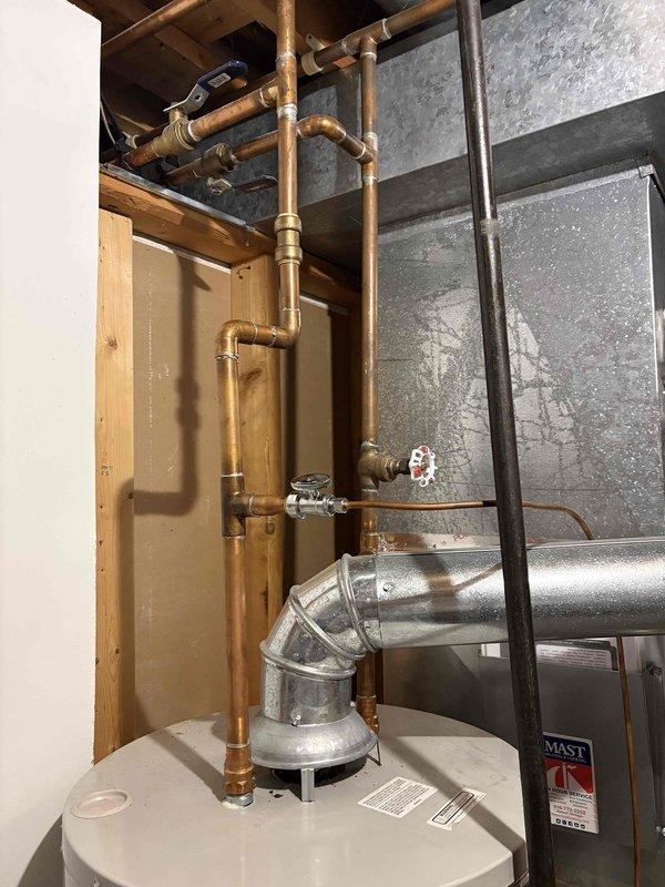 Responded to no hot water complaint on 15-year-old Bradford White water heater. Upon inspection, evaluated existing water heater installation including copper supply lines, brass shut-off valves, and venting system in utility space. Documented equipment condition through photographs showing aged copper piping with oxidation, multiple shut-off valves with red handles, and metallic flex duct venting configuration. Assessed water heater and associated plumbing infrastructure to determine system failure and provided estimate for water heater replacement due to unit age and loss of hot water production.