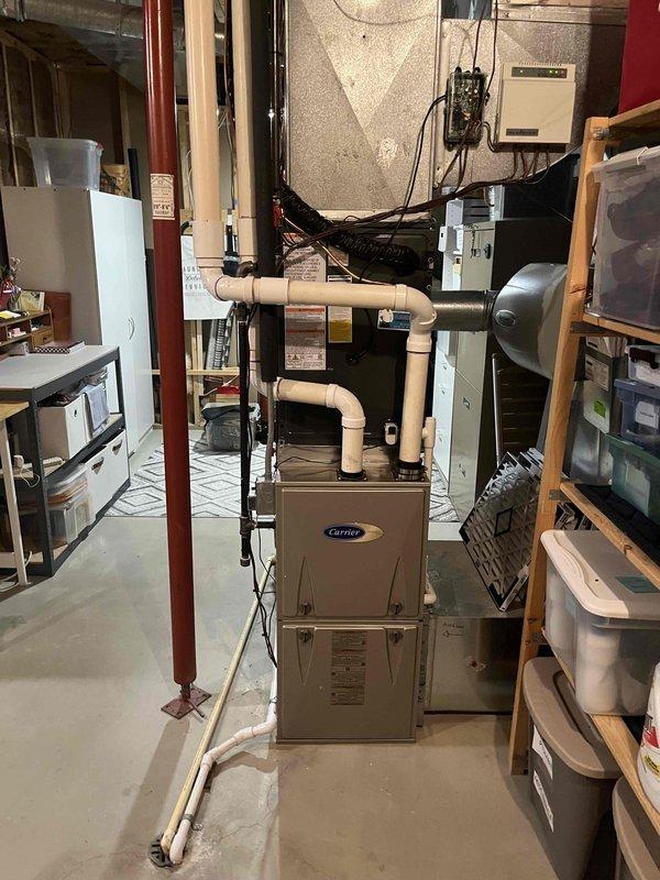 Complete air conditioning system replacement performed in residential basement utility area. Removed existing AC unit and installed new Carrier brand system with corresponding furnace integration. Completed all necessary ductwork connections including metallic supply ducts and black flexible return ductwork. Installed white PVC condensate drain piping with proper routing and termination. Verified electrical connections to control panel and ensured proper integration with existing utility infrastructure including gas lines and plumbing systems. System tested for proper operation, airflow verified, and all safety controls confirmed functional.
