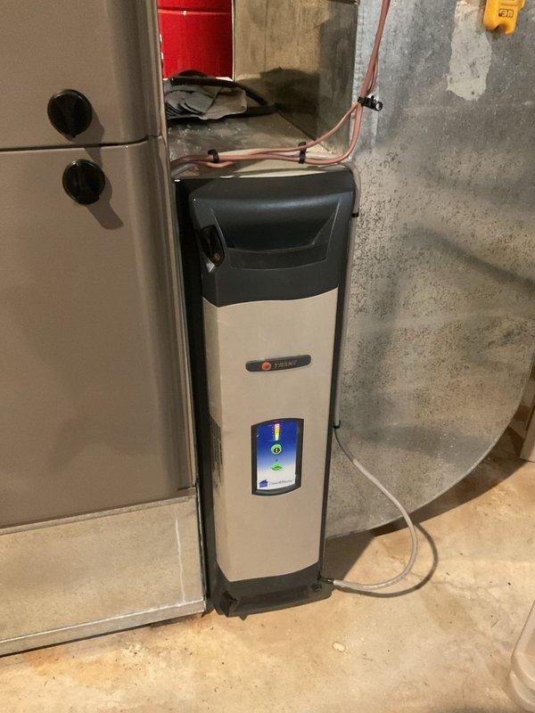 Responded to service call for Trane air handler displaying compressor filter error code and producing warm air from vents. Upon arrival, inspected 19-year-old Trane HVAC system located in basement utility area. Verified system status via digital control panel showing active fault code. Examined air handler unit, refrigerant line connections, and associated components for proper operation. Documented equipment condition and installation with photographic evidence showing copper refrigerant lines with insulation, wall-mounted electrical components, and overall system configuration. System evaluated for airflow restrictions, filter status, and compressor functionality to diagnose warm air issue and resolve error code condition.
