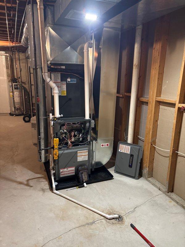 Completed full HVAC system installation including new furnace and air conditioning unit. Interior furnace unit installed in basement utility area with proper electrical connections, ductwork integration, and plenum assembly. Exterior condensing unit positioned on concrete pad along side of house with refrigerant lines and electrical conduit properly routed and connected. All components tested and operational upon completion of installation.