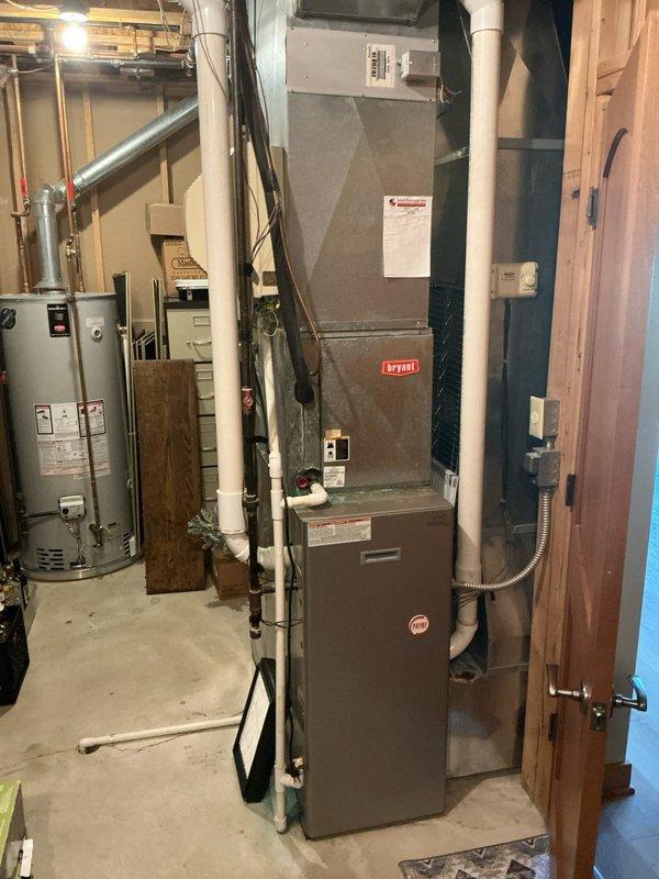 Responded to service call for non-operational furnace and air conditioning system. Upon arrival, inspected existing Bryant brand forced-air heating system and associated HVAC equipment located in basement mechanical room. Evaluated current furnace unit showing typical wear and dust accumulation consistent with operational age. Assessed air handling components, ductwork connections, and electrical control systems mounted on upper portion of equipment. Examined PVC condensate drainage piping, copper refrigerant lines with shutoff valves, and galvanized metal ductwork distribution system. Documented equipment configuration including zone control components and filter access panels. Reviewed water heater proximity and clearance requirements for replacement considerations. Provided comprehensive estimate for complete furnace and air conditioning system replacement based on equipment condition assessment and customer heating and cooling needs.