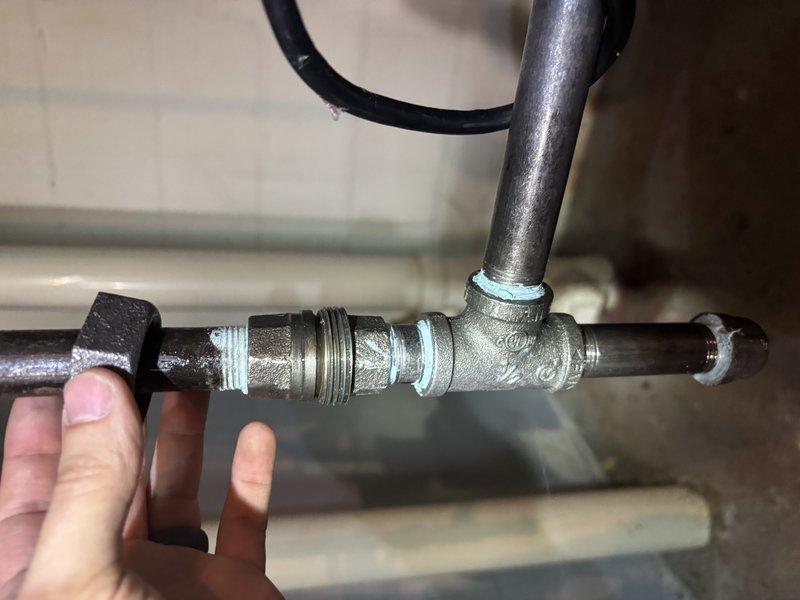 Completed annual cooling maintenance on 1-year-old Carrier unit model WT 06-2034. Inspected and photographed plumbing connections and pipe fittings in utility area, noting threaded unions with Teflon tape sealing at multiple junction points. All mechanical components found in functional condition with age-appropriate wear patterns on galvanized piping and connections.