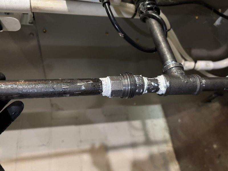 Completed annual cooling maintenance on 1-year-old Carrier unit model WT 06-2034. Inspected and photographed plumbing connections and pipe fittings in utility area, noting threaded unions with Teflon tape sealing at multiple junction points. All mechanical components found in functional condition with age-appropriate wear patterns on galvanized piping and connections.