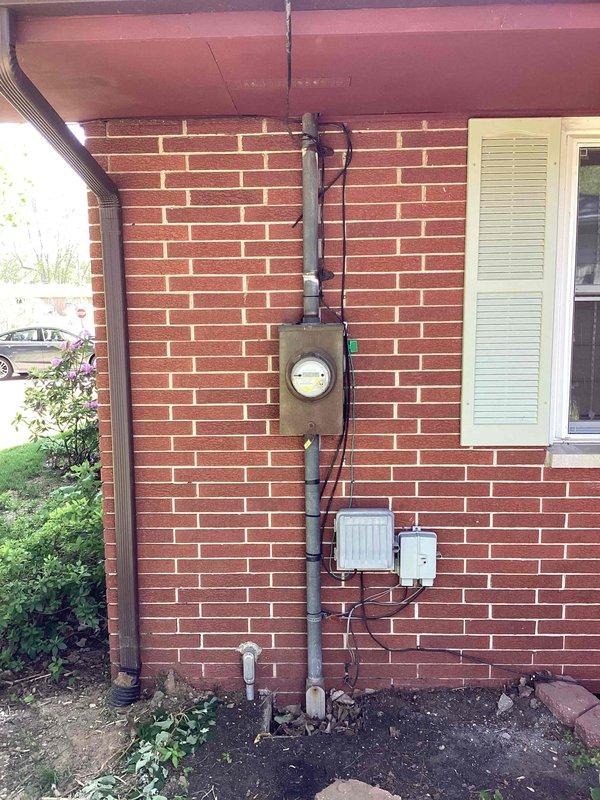 Completed estimate for new single-zone ductless mini-split system installation at residential property. Evaluated exterior brick wall for outdoor condenser unit placement and assessed electrical service panel location in attic space for proper power supply routing. Photographed proposed installation areas including exterior wall near existing electrical meter and main electrical panel with existing conduit runs to determine equipment placement, refrigerant line routing, and electrical connection requirements for wall-mounted indoor air handler and outdoor condensing unit.