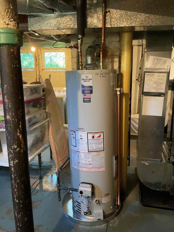 Completed installation of 40-gallon tall natural gas water heater in residential basement utility area. Removed existing unit and installed new Bradford White water heater with proper venting and copper pipe connections to overhead plumbing system. Connected gas supply line, verified all safety controls, and ensured proper clearances from surrounding HVAC equipment and structural supports. System tested and operational upon completion.