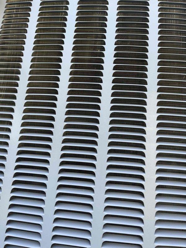 Completed annual cooling maintenance on 9-year-old EnergiAir system under warranty through November 2026. Inspection revealed significant dirt and debris accumulation on exterior ventilation louvers and condenser coils, particularly in upper sections. Documented equipment condition with photographs showing contaminated coil fins and soiled air intake grills requiring attention for optimal system performance.