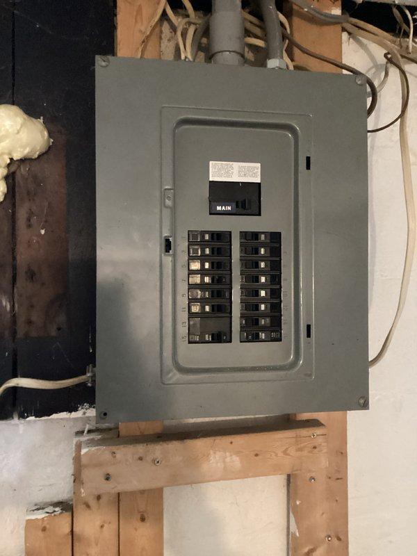Completed comprehensive electrical club inspection identifying multiple safety concerns. Main electrical panel examined showing proper breaker arrangement but located in unfinished area with exposed framing requiring attention to code compliance. Critical hazard identified at ceiling light fixture with improper wire support, exposed wiring through damaged ceiling opening, and significant deterioration around penetration point creating potential shock and fire risk. Documented all deficiencies with photographic evidence and recommended immediate repairs to ceiling fixture installation and proper wire management to meet current electrical safety standards.