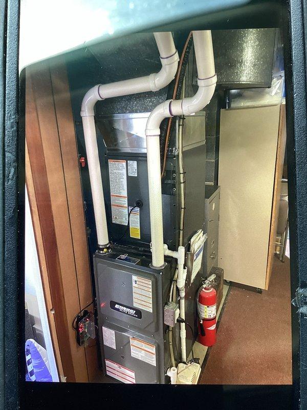 Successfully completed add-on air conditioning system installation to existing forced-air heating system. Installed new outdoor condensing unit on level concrete pad against exterior wall with proper clearances maintained from fence line and structure. Mounted electrical disconnect box on exterior siding and ran refrigerant line set and electrical conduit from outdoor unit into mechanical room. Inside utility closet, integrated new air handler component with existing furnace system. Installed proper PVC venting through roof for combustion air and exhaust. All refrigerant lines properly insulated and secured along exterior wall. System tested for proper operation, refrigerant charge verified, and airflow balanced. Fire safety equipment confirmed in place within mechanical room. Installation meets all code requirements with professional routing of all utilities and proper equipment placement for serviceability.