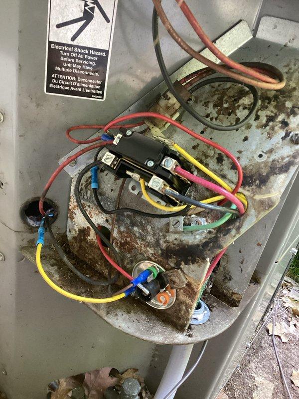 Responded to no cooling call on 20-year-old Comfortmaker R22 system with history of rodent damage from previous season that had caused grounded 24V wiring and corroded dual capacitor and contactor. Upon arrival, accessed condenser unit and documented extensive interior corrosion and rust throughout cabinet from prolonged moisture exposure. Inspected electrical connections and wiring harness at contactor and terminal block, noting deteriorated condition of components. Photographed damaged areas showing rust accumulation at base of unit and around connection points, as well as exterior disconnect and utility boxes. Homeowner authorized remotely via phone after reviewing documented conditions. Due to age of equipment, R22 refrigerant type, extent of previous rodent damage, and current corrosion issues, recommended system replacement as most cost-effective solution versus ongoing repairs.