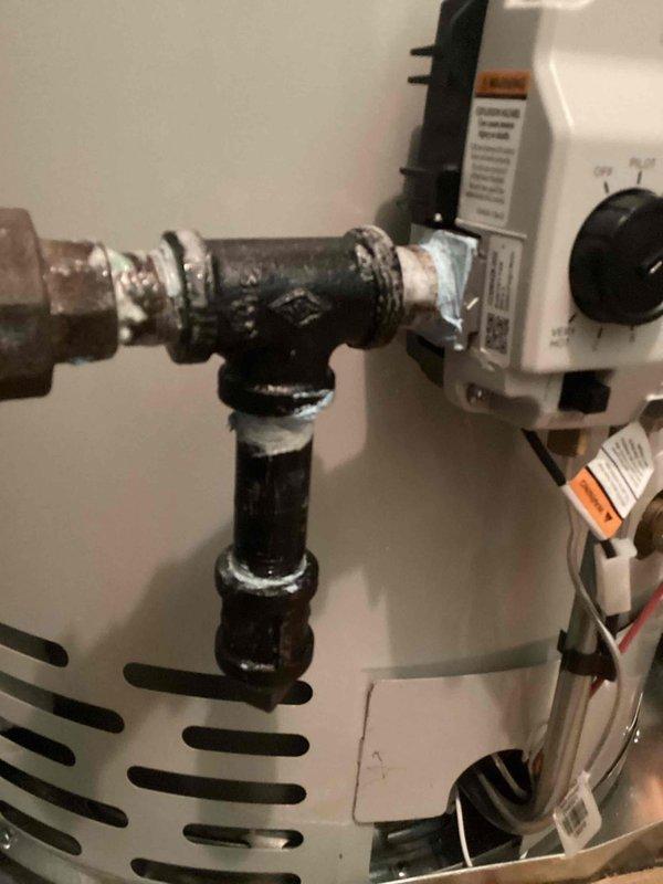 Responded to emergency service call for reported gas leak at water heater. Upon arrival, performed comprehensive safety inspection of gas-fired water heater unit and associated plumbing connections. Visual inspection revealed heavily corroded T-fitting and pipe assembly at top of water heater with significant oxidation, mineral buildup, and surface degradation on galvanized metal components. Conducted gas leak detection test using approved methods to identify source of reported leak. Inspected all gas line connections, pressure relief valve, temperature and pressure settings, and venting system for proper operation and code compliance. Documented existing conditions of deteriorated piping infrastructure through photographic evidence showing advanced corrosion on fittings and connections. Advised on safety concerns related to aging plumbing components and recommended immediate corrective action to address compromised pipe fittings that pose potential leak hazards. Unit control panel and