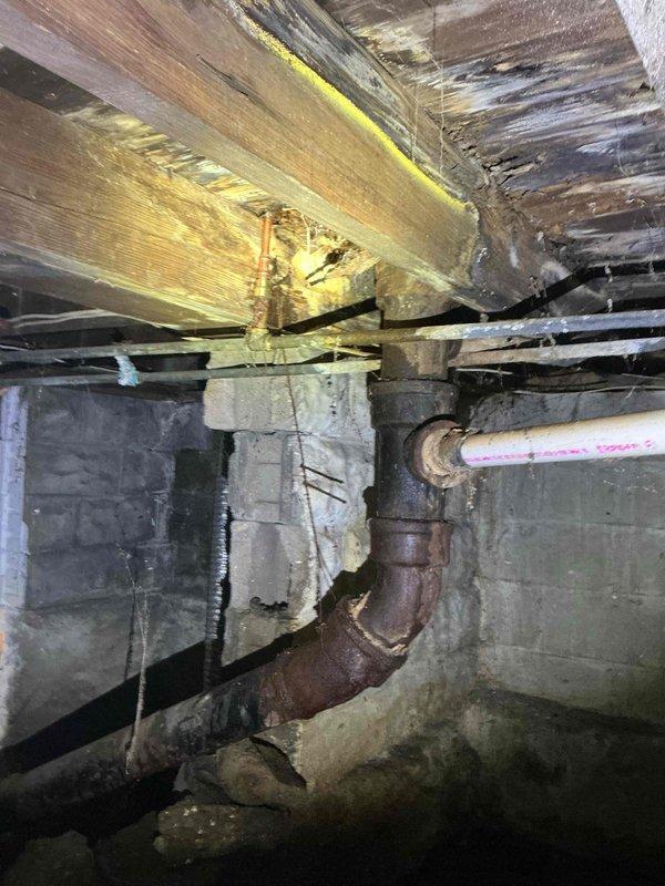 Responded to water leak in basement originating from toilet supply line on upper floor. Upon inspection, identified failed water supply line connection at toilet fixture with visible water damage and staining around base. Investigation of basement area revealed severely corroded metal piping in the plumbing system beneath the structure, with active water intrusion from the compromised supply line above. Shut off water supply, replaced defective supply line and connection hardware at toilet fixture, verified proper installation and tested system for leaks. Confirmed no additional water flow to basement area and advised property owner of the deteriorated condition of older metal piping observed in crawl space that may require future attention.