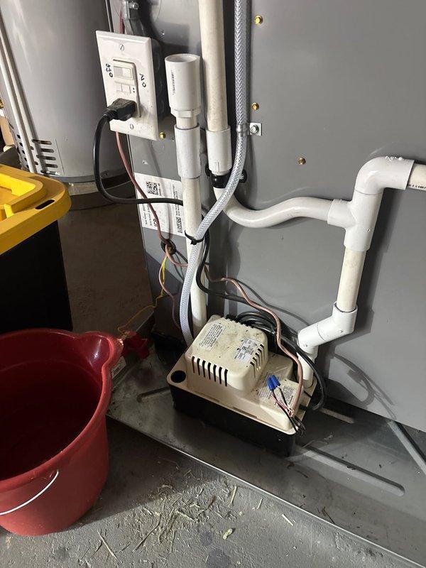Responded to water leak in basement mechanical room. Upon inspection, identified active leak originating from PVC plumbing connections near ceiling joists above HVAC equipment and water heater. Documented existing conditions with photos showing water damage potential to electrical components, including outlet box and transformer mounted on wall below affected piping. Traced leak source to compromised joint in drainage system running along ceiling beams. Repaired faulty connection, secured all loose PVC fittings, and verified proper slope of horizontal drain lines. Tested system under full flow conditions to confirm leak resolution. Advised monitoring area for any residual moisture and recommended evaluation of electrical components for water exposure damage.