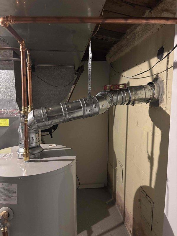 Corrected water heater venting system to meet code requirements by adjusting the horizontal vent pipe slope using proper support methods. The flexible metal duct was repositioned and secured with appropriate hangers to ensure proper drainage and prevent condensation accumulation, resolving the inspection violation for improper venting slope.