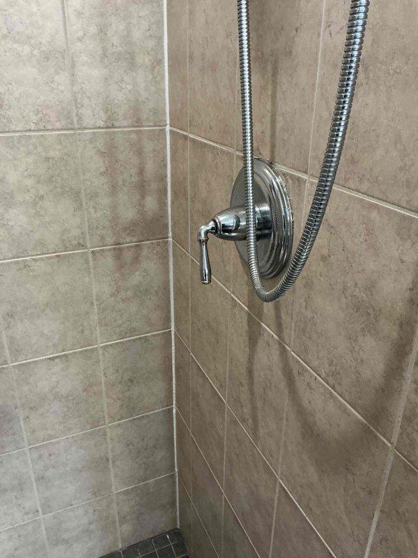 Responded to shower faucet failure with loose, spinning handle and no water delivery. Upon inspection, found valve stem had become detached from cartridge assembly, causing handle to spin freely without engaging water control mechanism. Removed decorative trim and handle to access valve cartridge. Replaced faulty cartridge and reinstalled handle assembly, securing all components properly. Tested operation and confirmed full water flow restoration and proper temperature control functionality.