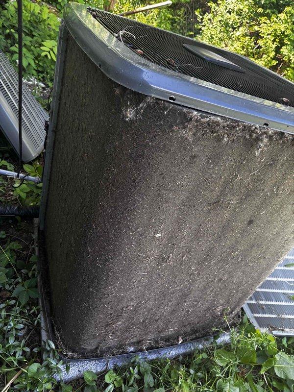 Completed annual cooling maintenance on EnergiAir system under warranty coverage. Upon arrival, found outdoor condenser unit in severely neglected condition with heavy accumulation of dirt, grime, organic growth, and mildew covering exterior surfaces. Side access panel was detached and lying on ground in vegetation. Unit exhibited extensive soiling on front-facing coil panel with thick grayish-brown debris buildup and streaking patterns indicating prolonged exposure without maintenance.

Performed comprehensive cleaning of condenser coils and exterior cabinet. Removed heavy debris accumulation from base and surrounding area. Reinstalled loose side panel. Inspected cooling fins and noted white residue along top protective cover edge. Completed standard tune-up procedures including electrical connection inspection, refrigerant level verification, and operational testing. System restored to proper working condition. Documented pre-service condition with photographs. Recommended increased 