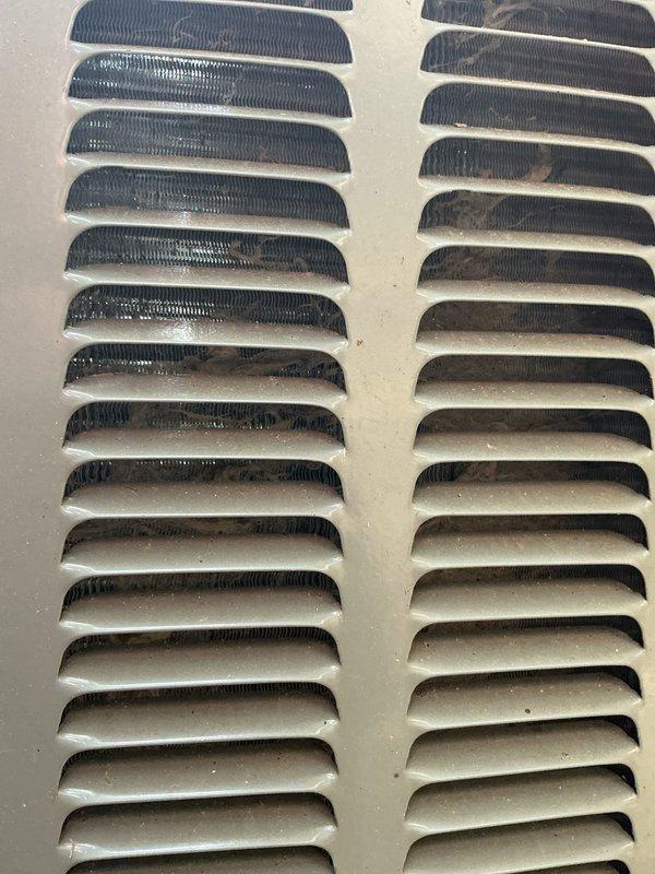 Completed annual cooling maintenance on 12-year-old EnergiAir system with 2019 condenser model. Performed comprehensive tune-up including inspection of outdoor condenser unit, which showed normal weathering and minor debris accumulation on protective grille and surrounding area. Noted significant dust and dirt buildup on interior ventilation grill with concentrated contamination on louvers, indicating need for improved filtration or more frequent filter changes.