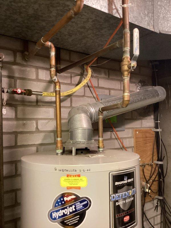 Conducted on-site evaluation of existing Bradford White Defender water heater system installed in 2004 to provide estimate options for both tankless and traditional tank-style replacement units. Documented current installation configuration including copper supply piping, venting system, gas connections, and observed condensation on horizontal piping indicating potential efficiency concerns with aging equipment.