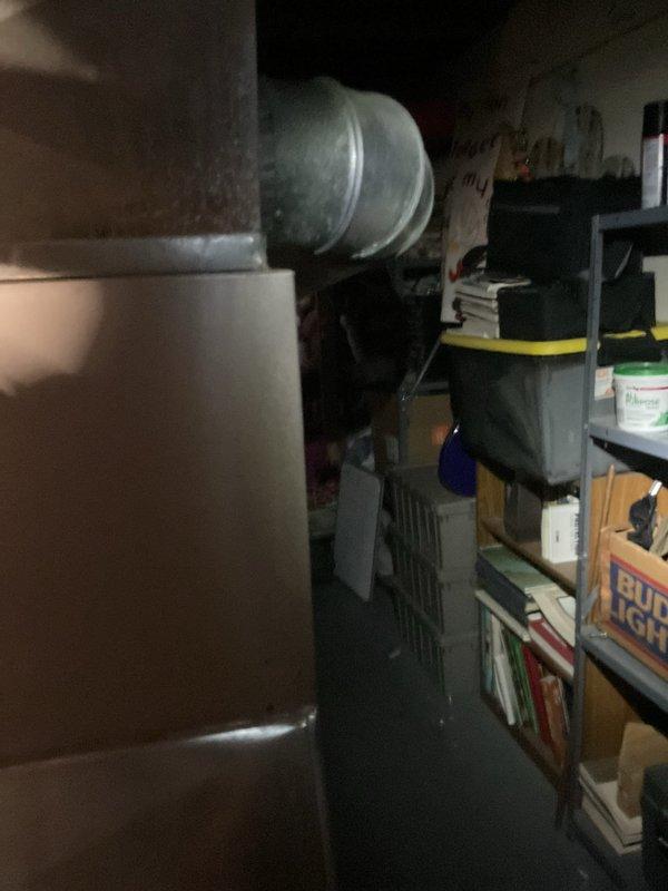 Responded to cooling complaint on 16-year-old Carrier system with inadequate cooling performance. Inspected indoor air handler unit located in basement utility area and verified system operation. Customer suspected low refrigerant charge as cause of reduced cooling capacity. Performed visual inspection of evaporator coil access panel and documented equipment condition with photos for service records.