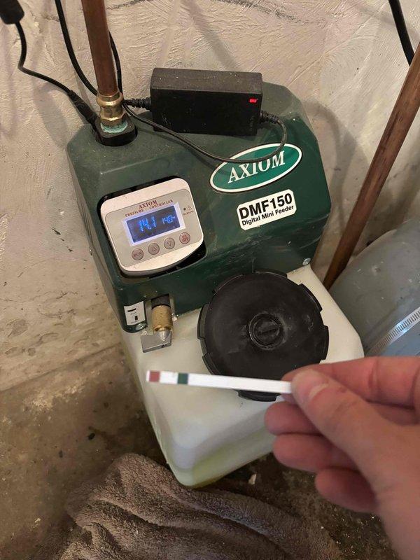Responded to no-heat call for residential boiler system. Upon inspection, found AXIOM DMF150 Digital Mini Feeder chemical treatment system displaying error codes on digital display. Tested and serviced the feeder unit, verified proper chemical levels in reservoir tank, and restored system to normal operation. System now heating properly and providing heat throughout home.