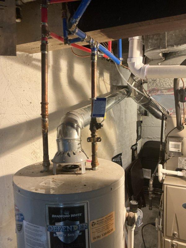 Completed estimate for replacement of existing 40-gallon Bradford White water heater with Defender Safety System. Documented current installation including copper and PEX plumbing connections, exhaust venting configuration, and clearance requirements in basement utility room. Photographed existing equipment specifications and surrounding HVAC components to provide accurate replacement proposal.