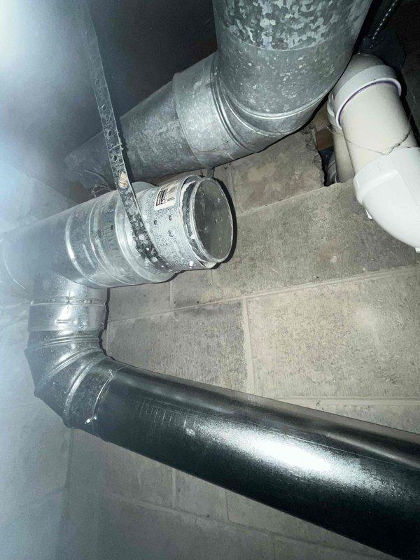 # IAQ Miscellaneous Service - B-Vent Modification

Responded to a no-charge service call to address B-vent configuration issues in the mechanical space. Upon inspection, identified improper temporary sealing on a 4" B-vent tee assembly with tape that required removal and proper termination.

Evaluated the existing vent configuration, which included galvanized metal ductwork with 90-degree elbows showing moisture accumulation, white PVC drainage piping, and black flexible insulated ductwork in the crawlspace area. Determined the optimal solution for proper venting compliance.

Removed temporary tape sealing from the 4" B-vent tee and installed appropriate cap to ensure proper termination. Alternatively assessed the option to remove the existing tee entirely and install a 5" to 4" single-wall reducer with a 4" 90-degree single-wall elbow for improved venting performance.

Verified all connections were secure and properly sealed according to manufacturer specifications and local code requ