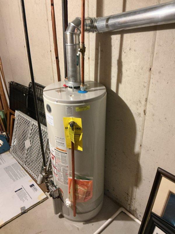 Responded to service call for 13-year-old tank-style water heater producing unusual noises while still providing hot water. Performed comprehensive inspection of unit, examining all plumbing connections, pressure relief valve, and heating elements. Assessed condition of copper supply lines, shut-off valves, and venting system. Evaluated sediment buildup as likely cause of noise based on unit age and operational symptoms. Documented current state of water heater with photographs showing all connections, labels, and surrounding utility space. Confirmed unit is functioning and producing hot water but recommended monitoring given age of equipment approaching typical service life expectancy. Provided assessment findings to customer regarding replacement considerations.