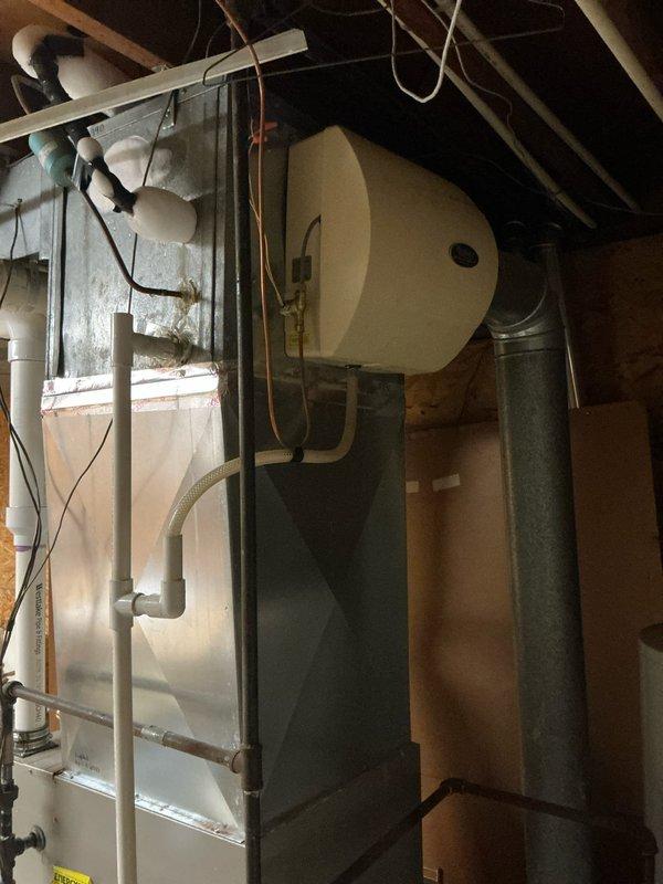 Responded to service call for non-operational air conditioning system at 9 AM. Conducted comprehensive assessment of residential HVAC installation located in basement mechanical room. Inspected Bryant furnace unit, metallic air handler with silver exterior finish, associated ductwork including large gray flexible ducts, white PVC condensate drain lines, and cylindrical expansion tank. Documented existing equipment configuration with photographs showing complete system layout, including exposed wiring, copper piping, galvanized ductwork with insulation, and all mechanical connections. Evaluated overall system condition and operational status to prepare detailed estimate for necessary repairs or replacement.