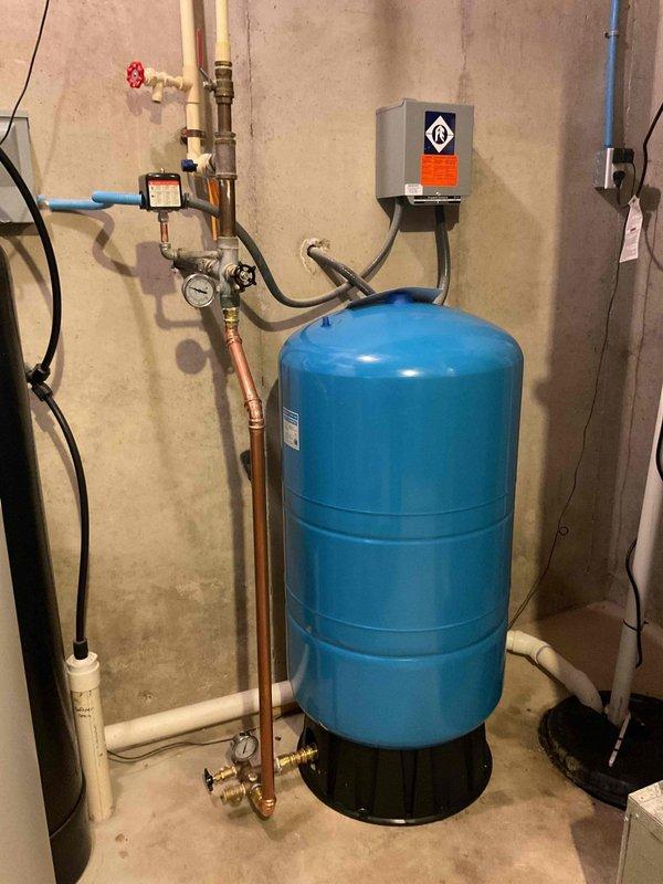 Completed well pressure tank replacement in residential utility space. Removed existing failed pressure tank and installed new blue cylindrical pressure tank with electronic pressure control system, including all necessary connections to existing copper supply lines, pressure gauge, shut-off valves, and electrical components. System tested and verified operational with proper pressure settings confirmed.