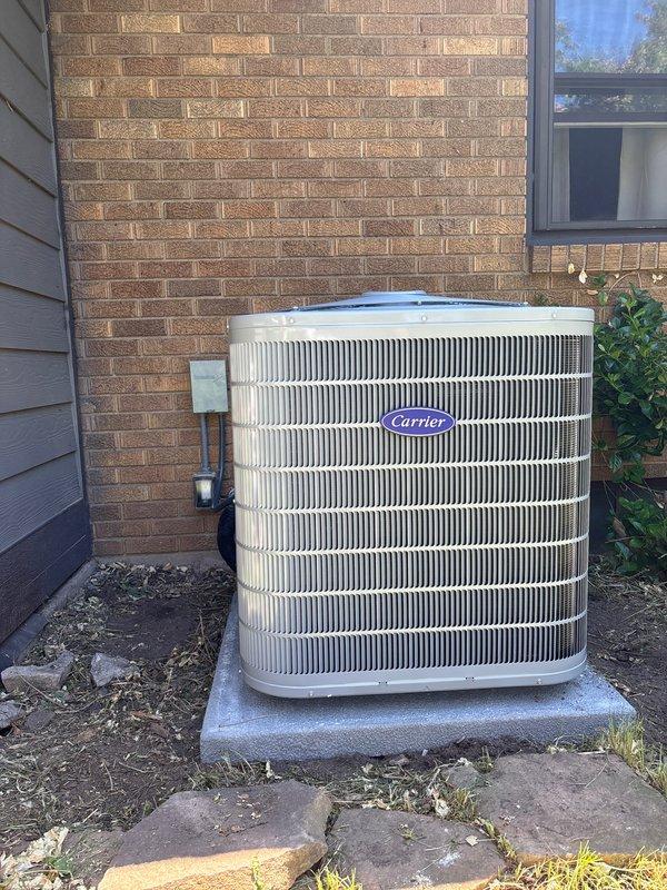Successfully completed add-on air conditioning system installation. Installed new Carrier condensing unit on concrete pad against exterior brick wall with proper clearances maintained. Unit positioned with adequate access for future service and airflow requirements. Mounted electrical disconnect box on brick wall with appropriate conduit routing to equipment. Ran refrigerant line set through wall penetration using insulated copper tubing with weather-resistant flexible conduit protection. Connected all electrical components per manufacturer specifications and local code requirements. Verified proper drainage and condensate line routing. System tested and confirmed operational with appropriate refrigerant charge and airflow measurements within acceptable parameters.