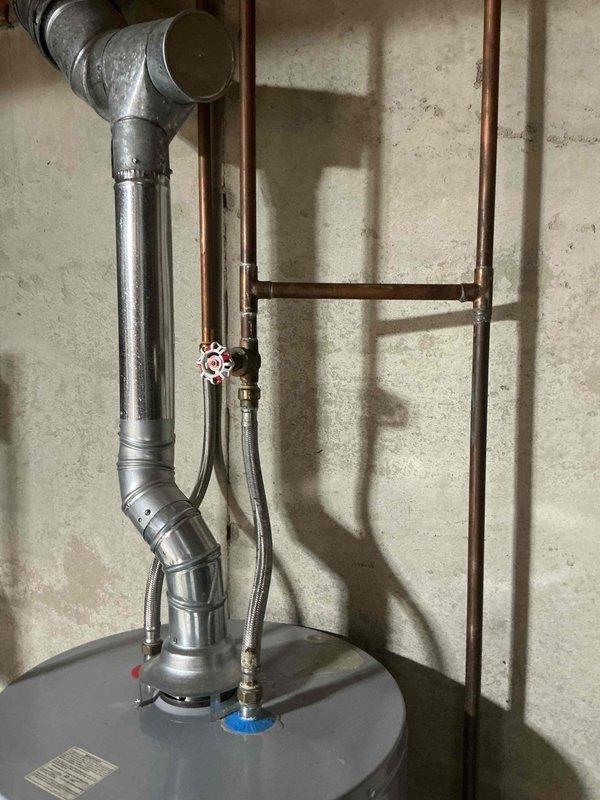 Responded to water leak at residential water heater. Upon arrival, inspected AO Smith water heater and associated plumbing connections. Identified leak originating from pipe connection at top of unit near shut-off valves. Assessed copper piping, galvanized ductwork, and brass fittings for source of water intrusion. Tightened connection at leaking pipe junction and verified all hot and cold water line connections were secure. Tested system operation and confirmed leak was resolved with no further water discharge observed.