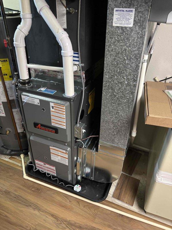 Completed full furnace installation in residential basement mechanical room. Installed new Amana furnace unit on wooden platform with proper PVC venting and condensate drainage piping routed vertically. Connected metal ductwork to existing system through ceiling joists, integrated with air handler cabinet, and ensured all manufacturer specifications and safety requirements were met for residential heating system operation.