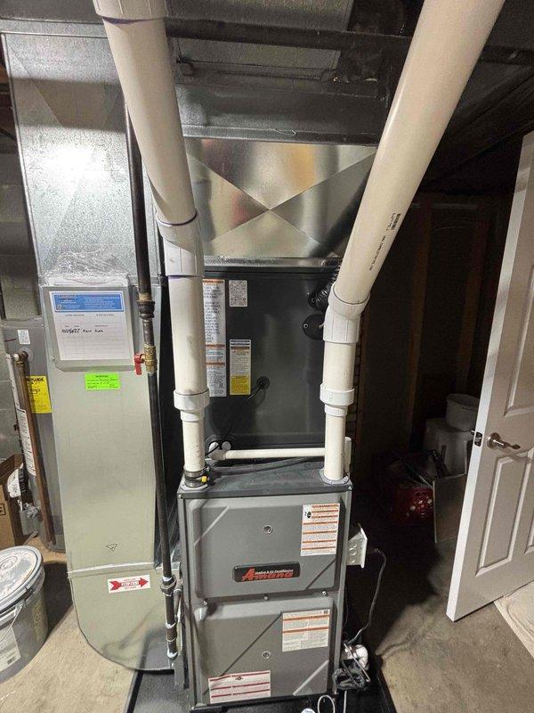 Completed full residential HVAC system replacement including installation of new Amana furnace unit in basement utility room with proper venting configuration using white PVC intake and exhaust pipes. Installed new air handler with refrigerant line connections and integrated system with existing metallic ductwork for whole-home air distribution. Mounted new outdoor condensing unit on concrete pad with appropriate clearances, connected electrical conduit and refrigerant lines to foundation penetration, and placed unit on gravel base for drainage. All equipment properly labeled with manufacturer specifications and safety warnings. System tested and verified operational upon completion.