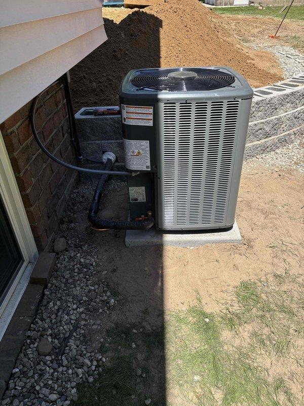 Completed full residential HVAC system replacement including installation of new Amana furnace unit in basement utility room with proper venting configuration using white PVC intake and exhaust pipes. Installed new air handler with refrigerant line connections and integrated system with existing metallic ductwork for whole-home air distribution. Mounted new outdoor condensing unit on concrete pad with appropriate clearances, connected electrical conduit and refrigerant lines to foundation penetration, and placed unit on gravel base for drainage. All equipment properly labeled with manufacturer specifications and safety warnings. System tested and verified operational upon completion.