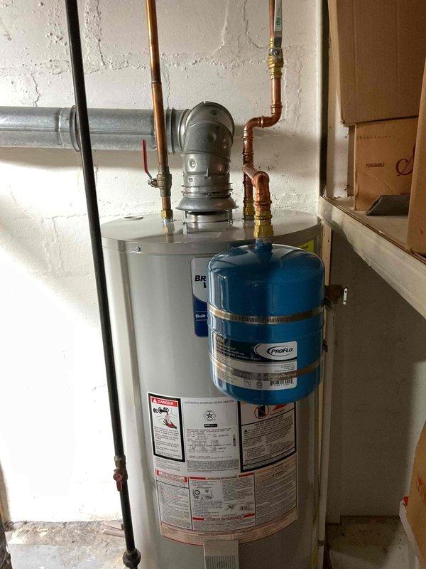Completed expansion tank replacement on residential water heater system. Installed new blue expansion tank with proper copper piping connections to existing water heater assembly, ensuring correct pressure relief valve integration and secure mounting. Verified Treon System control unit operation with green status indicator illuminated and confirmed water alarm system functionality upon completion.
