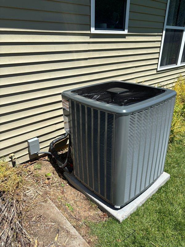 Completed full HVAC system installation including new furnace and air conditioning unit. Installed dark gray furnace in basement utility area with dual white PVC intake and exhaust venting, positioned on drain pan with proper clearances. Mounted outdoor condensing unit on concrete pad against exterior wall with electrical disconnect box, conduit, and all necessary connections to building electrical system. All ductwork connections, refrigerant lines, and drainage systems installed per manufacturer specifications and local code requirements.