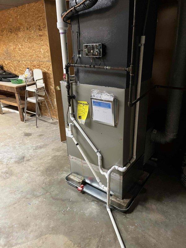 Completed full HVAC system replacement including indoor furnace unit and outdoor condensing unit. Installed new furnace in basement utility area with proper refrigerant line connections, condensate drainage via PVC piping, and electrical hookup through junction box. Mounted unit on drain pan with appropriate fittings for moisture management. Ran black insulated refrigerant lines from furnace to outdoor unit, ensuring proper routing and insulation throughout. Installed outdoor condensing unit on existing concrete pad adjacent to building foundation with refrigerant lines penetrating exterior wall and connecting to indoor system. Verified all electrical connections, refrigerant line integrity, and drainage systems operational. System tested and confirmed functioning properly upon completion.
