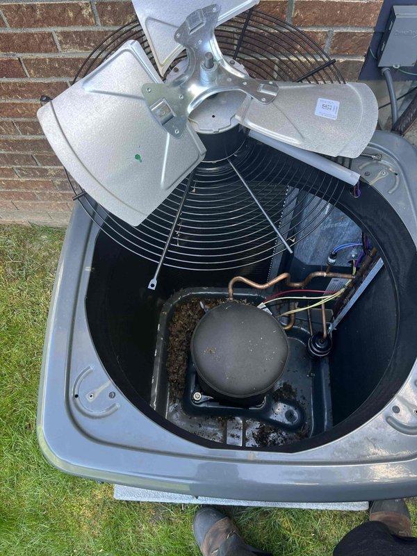 Completed annual cooling maintenance on split-system air conditioning unit. Opened and inspected condenser unit, accessing compressor, refrigerant lines, and fan assembly. Noted significant dirt and debris accumulation in unit base and around compressor requiring cleaning. Documented internal component condition with photographs showing copper refrigerant lines, condenser fan motor, and compressor assembly. All major components accessible and operational at time of inspection.