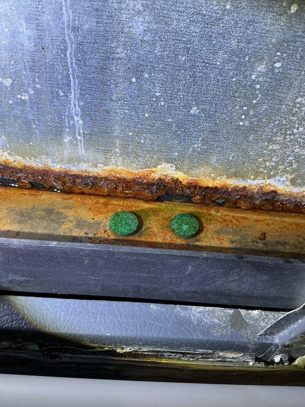 Completed annual cooling maintenance on EnergiAir system with 2023 condenser model. Inspected outdoor unit ventilation louvers and found them functioning properly with minor surface wear on yellow-green painted housing. Documented significant moisture condensation buildup on upper equipment surfaces and extensive rust corrosion on horizontal metal brackets and mounting components, indicating prolonged exposure to moisture and potential drainage issues. Recommended monitoring unit for continued corrosion progression and consideration of rust remediation to prevent structural deterioration of affected components.