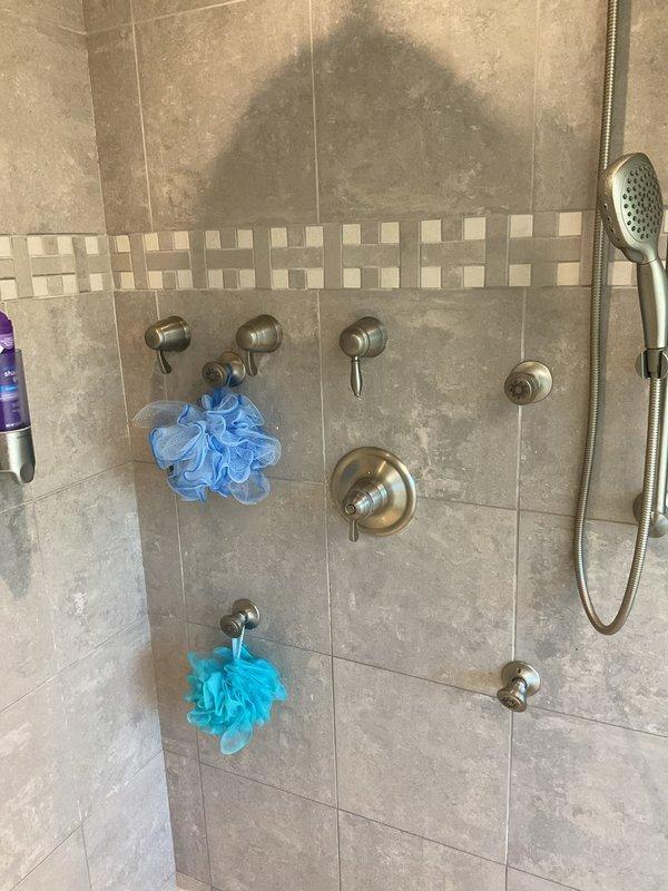 Responded to multi-function shower system requiring cartridge replacement after accidental damage during previous service. Successfully removed and replaced damaged cartridge in shower control valve. Tested all shower fixtures including wall-mounted body sprays, handheld shower head, and temperature/flow controls to verify proper operation. System restored to full functionality with no leaks detected. Work completed in approximately 2 hours.