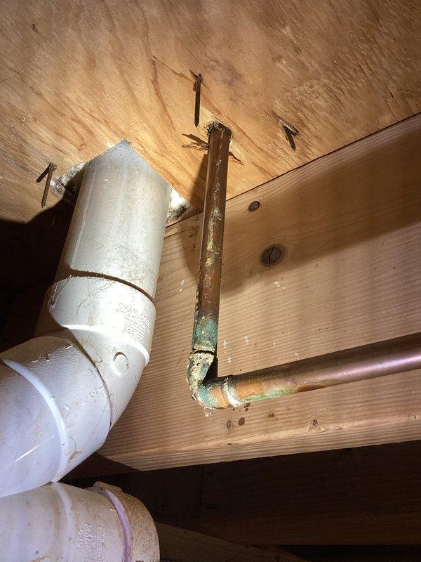 Responded to active plumbing leak originating from toilet fixture with water intrusion into basement area. Upon inspection, identified corroded copper supply line with significant oxidation and patina buildup at joint connection point in crawl space above affected area. Replaced deteriorated copper piping and installed new braided stainless steel flexible supply line with chrome fittings, ensuring proper connection to shut-off valve and fixture. Verified all connections were secure and leak-free, tested water flow, and confirmed no further water intrusion into basement space.