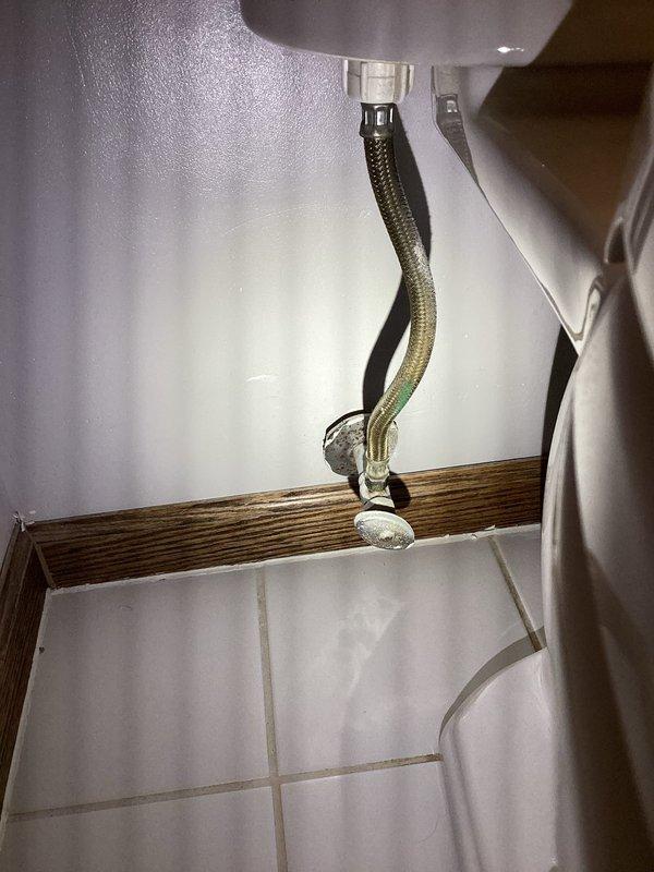 Responded to active plumbing leak originating from toilet fixture with water intrusion into basement area. Upon inspection, identified corroded copper supply line with significant oxidation and patina buildup at joint connection point in crawl space above affected area. Replaced deteriorated copper piping and installed new braided stainless steel flexible supply line with chrome fittings, ensuring proper connection to shut-off valve and fixture. Verified all connections were secure and leak-free, tested water flow, and confirmed no further water intrusion into basement space.
