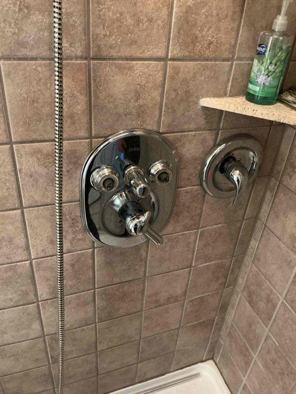 Responded to service call for 14-year-old shower faucet system in historic 1832 stick-built residence. Assessed downstairs shower that had been out of service for approximately one year due to broken door, missing handles, and disconnected pipes. Inspected thermostatic mixing valve assembly with multiple controls and chrome fixtures. Reconnected displaced piping, replaced missing control handles on the multi-function valve system, and verified proper operation of both handheld and fixed showerhead components. Tested water flow and temperature control functionality through all valve positions. Restored shower to full working condition with all controls properly functioning.