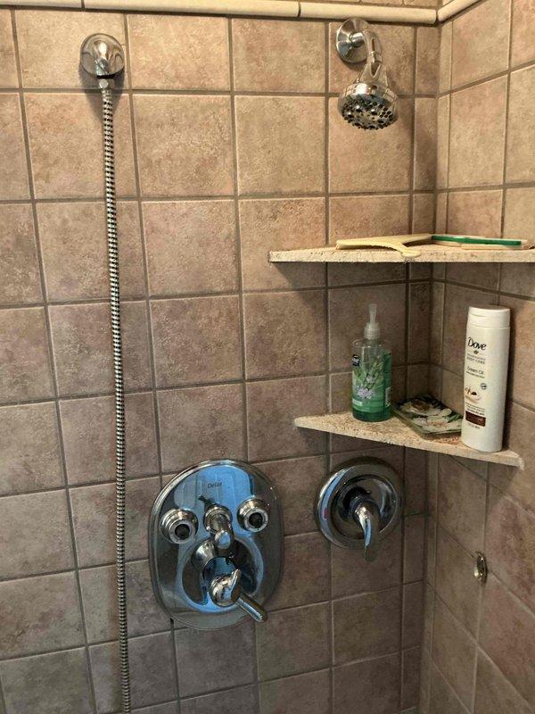 Responded to service call for 14-year-old shower faucet system in historic 1832 stick-built residence. Assessed downstairs shower that had been out of service for approximately one year due to broken door, missing handles, and disconnected pipes. Inspected thermostatic mixing valve assembly with multiple controls and chrome fixtures. Reconnected displaced piping, replaced missing control handles on the multi-function valve system, and verified proper operation of both handheld and fixed showerhead components. Tested water flow and temperature control functionality through all valve positions. Restored shower to full working condition with all controls properly functioning.