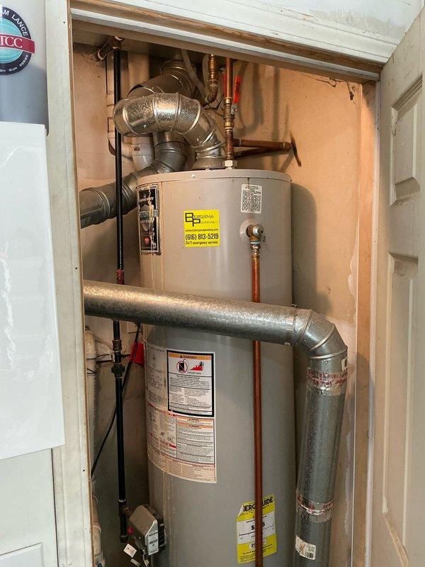 Completed free estimate for replacement of 20-year-old Bradford White water heater located in utility closet. Inspected existing installation including water heater, associated copper piping, brass fittings, and connection points. Documented current equipment configuration with two cylindrical units, metallic ductwork, and plumbing assembly for accurate replacement specifications.