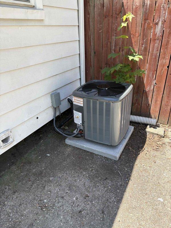 Completed full HVAC system replacement including outdoor condensing unit and indoor air handler. Removed existing equipment and installed new silver/gray condenser unit on concrete pad in side yard with proper refrigerant line connections and electrical disconnect. Installed new furnace/air handler in basement utility area with associated ductwork connections and electrical wiring. All refrigerant lines, electrical conduit, and drainage properly routed and secured. System tested and verified operational upon completion.