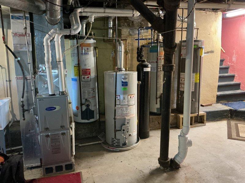 Completed rental inspection of basement mechanical room. Inspected and documented one water heater as requested (furnace excluded from inspection as unit is new). Photographed water heater installation, surrounding HVAC equipment including Carrier furnace, plumbing connections, exposed ductwork, and overall mechanical room conditions for rental property documentation purposes.