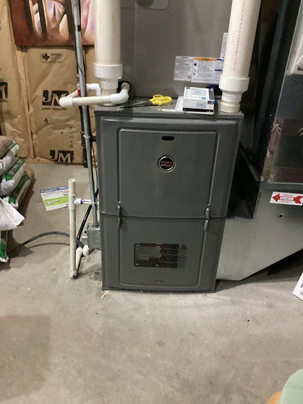 Completed conversion estimate for LP to natural gas system. Documented existing Ruud furnace installation and water heater configuration in basement utility area, photographing current equipment setup and surrounding infrastructure to assess conversion requirements and provide accurate pricing for fuel source changeover.