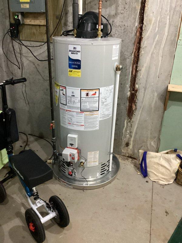 Completed conversion estimate for LP to natural gas system. Documented existing Ruud furnace installation and water heater configuration in basement utility area, photographing current equipment setup and surrounding infrastructure to assess conversion requirements and provide accurate pricing for fuel source changeover.