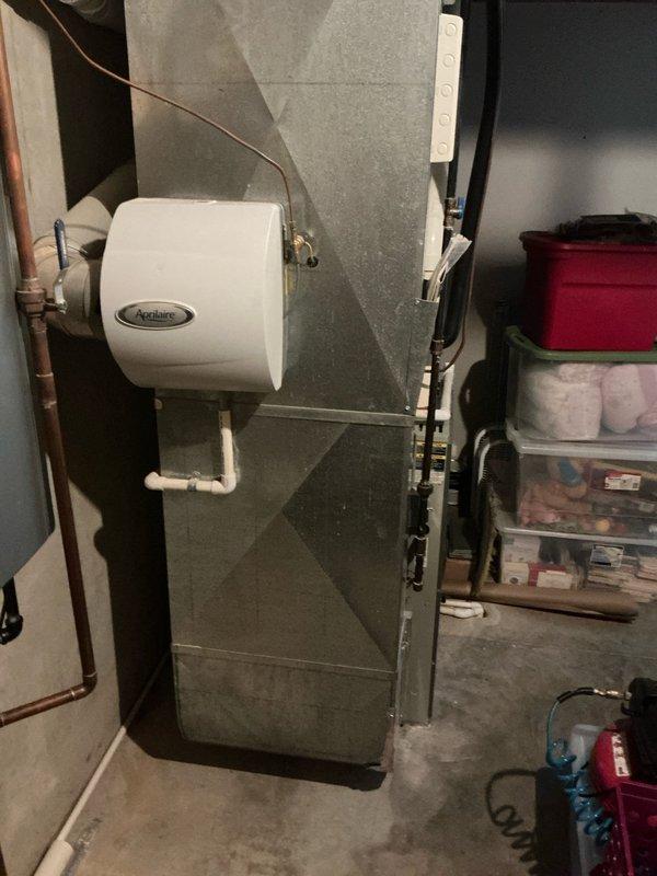 Completed estimate for replacement of residential HVAC system including 20-year-old air conditioning unit and furnace located in basement utility area. Assessed existing equipment configuration including Aprilaire whole-house humidifier integration with copper piping connections, evaluated basement mechanical room layout with water treatment systems, sump pump, and dehumidifier present. Discussed potential generator installation options with homeowner and provided comprehensive replacement recommendations for aging heating and cooling equipment.